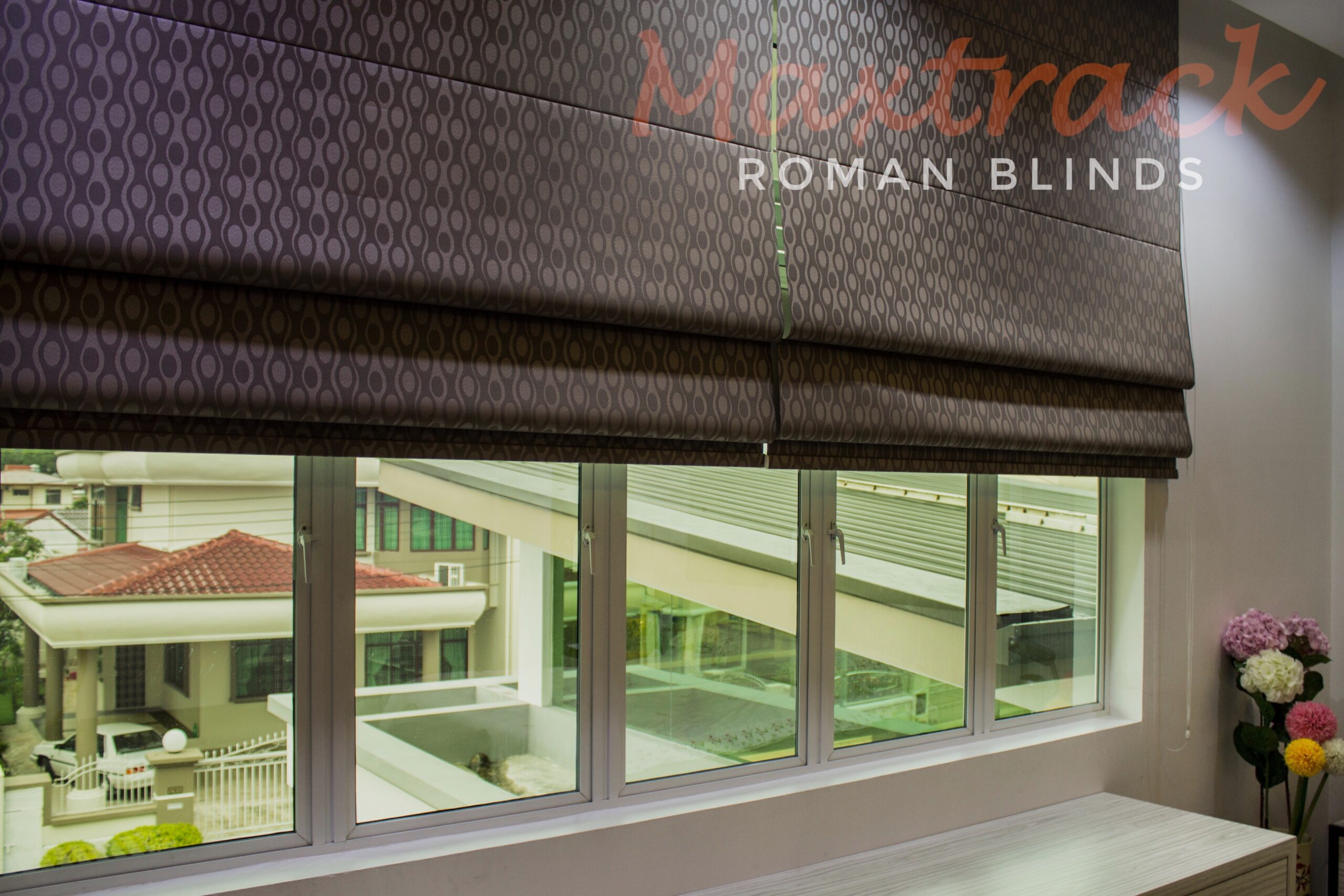 Maxtrack roman blinds with patterned fabric installed above bedroom windows, adding soft privacy, filtered daylight, and a refined decorative finish.