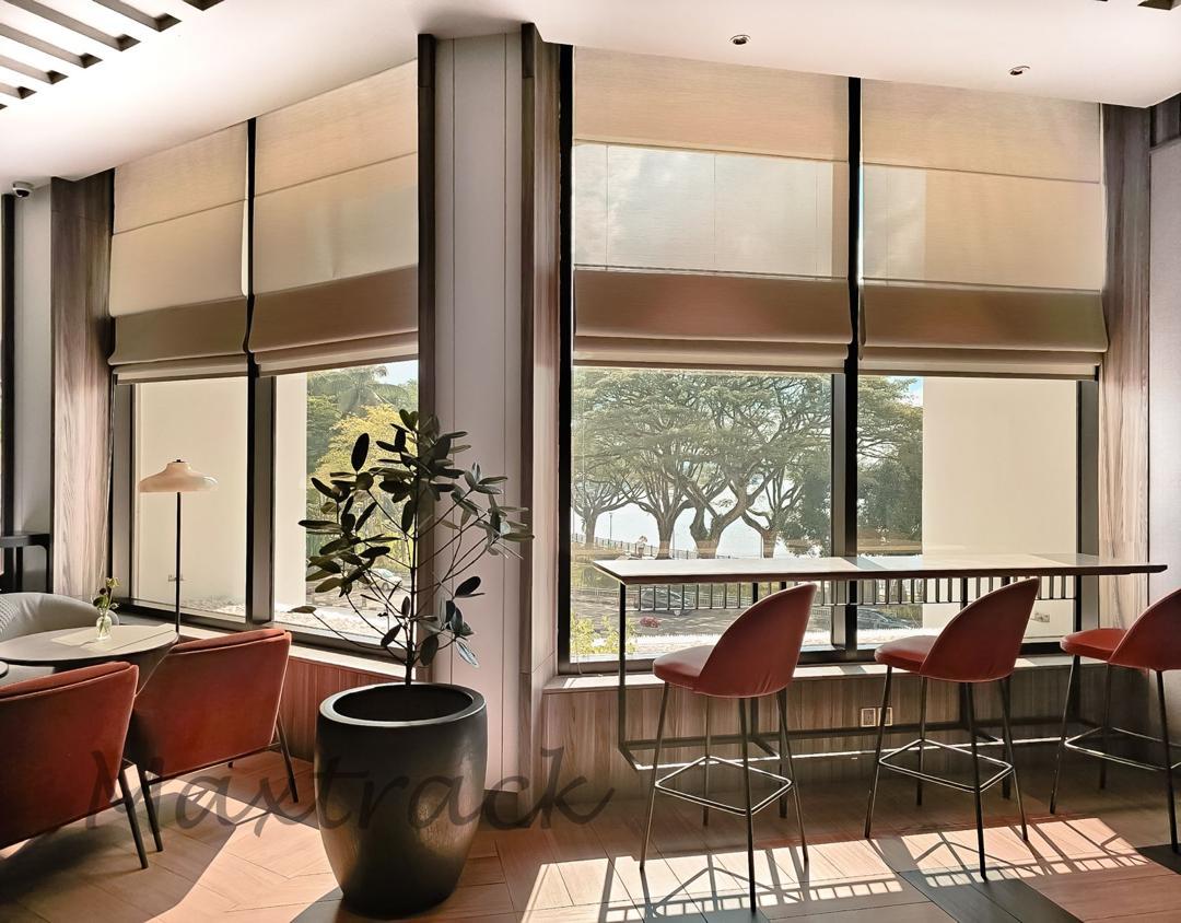 Roman blinds installed across tall cafe windows, creating soft daylight control, privacy, and a warm refined interior setting.